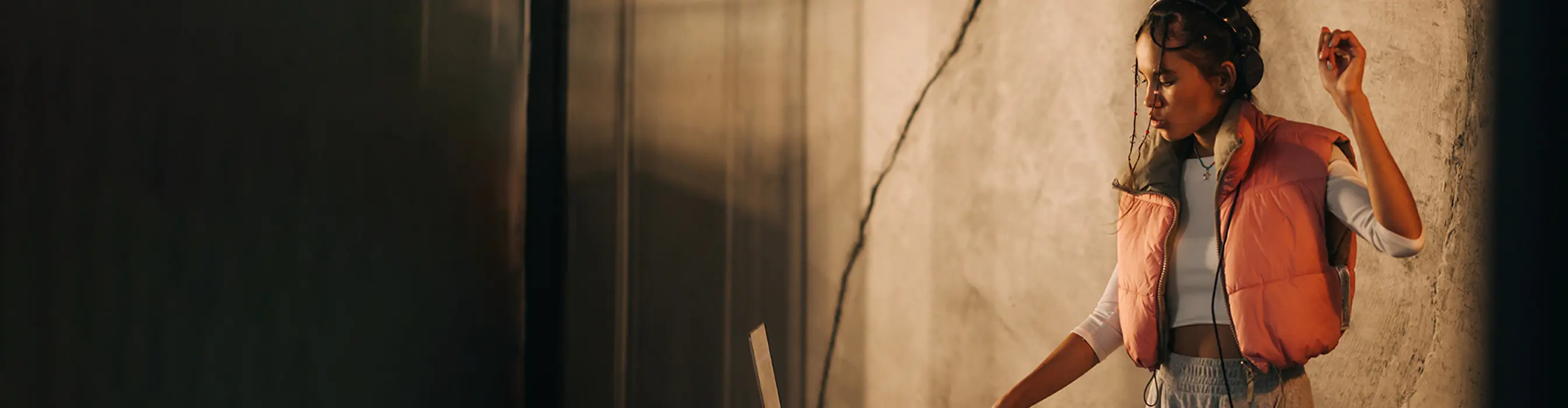 Wide banner image of a girl in an orange gilet DJing