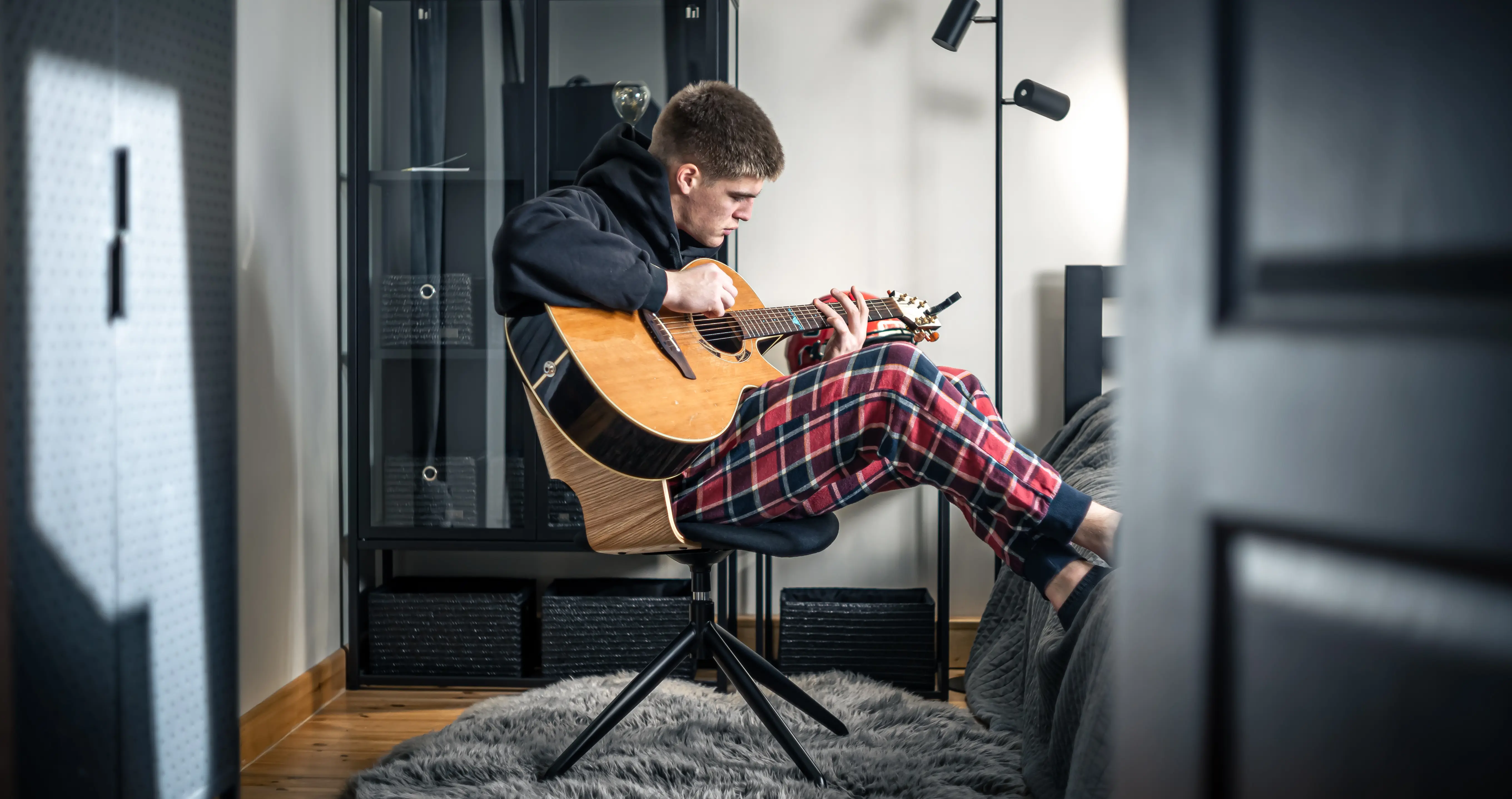 A young man sat in his bedroom playing guitar