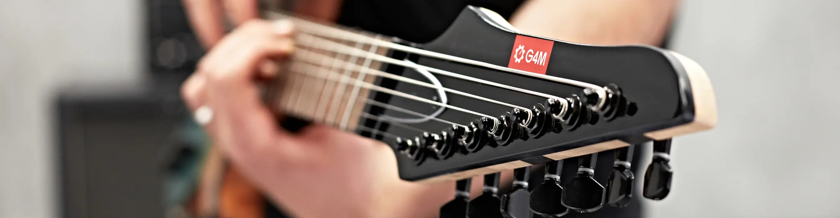 Close up of the head of a G4M guitar being played
